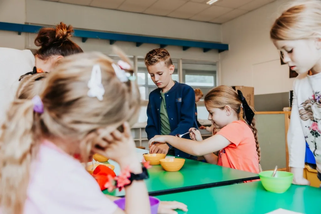 Kinderen eten samen aan tafel bij de BSO